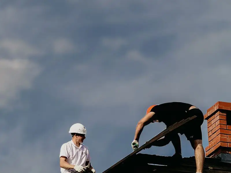 Roofers installing panel near chimney
